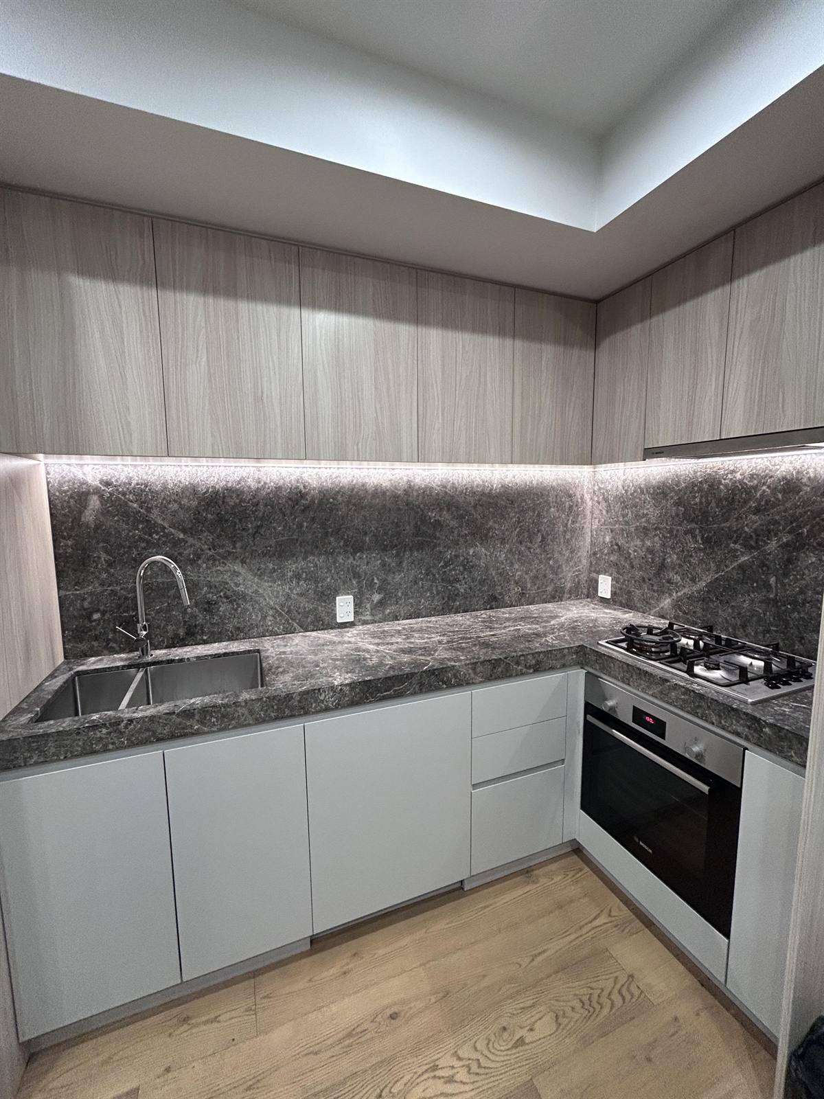 A freshly cleaned modern kitchen with stone benchtops and a marble splashback